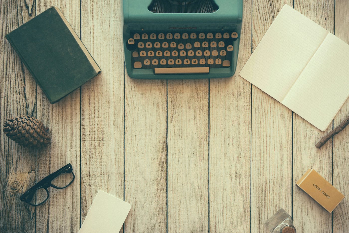 Una máquina de escribir, un libro y un cuaderno